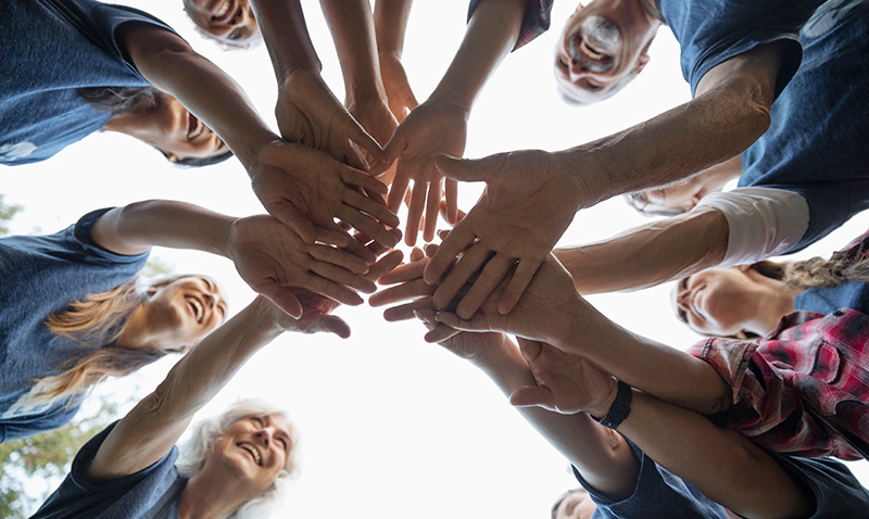 Image of a group of people standing in a circle and joining hands